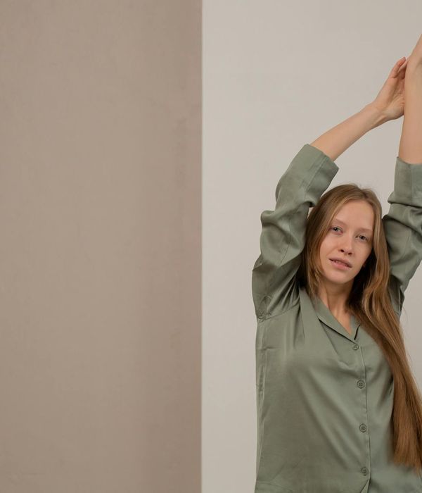A serene woman in a gentle stretching pose against a calm blue background.